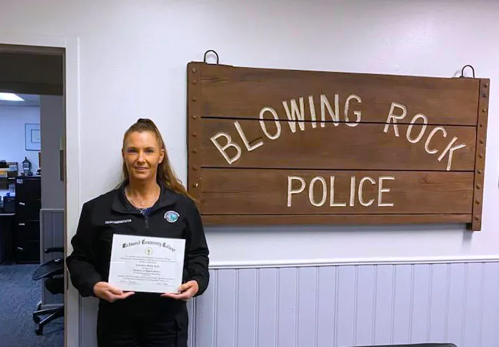 911 Communications & Operations graduate Casandra Reid holds her degree by sign for Blowing Rock Police Department.